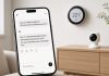 Google Home AI Agent MCP Lets Claude, ChatGPT, and Others Control Nest Devices Smartphone showing a chat about lights and temperature beside a circular wall thermostat and a small indoor camera