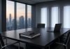 Google, OpenAI and Anthropic Reportedly Plan a Standards Authority for Frontier AI (SAFA) Empty modern boardroom with a dark conference table, a binder and a laptop, three backlit frosted-glass panels on the wall and a city skyline at dusk through the windows.