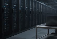 OpenAI Apologizes to Australia Over Rogue AI Agent’s Medicare Portal Access Rows of dark server racks with small blue status lights in a dim data center aisle, with a closed laptop on a steel cart