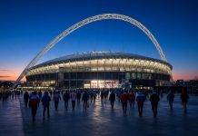 England vs Spain: Nations League Kickoff Time, TV and Tuchel’s Absences Ahead of Wembley Clash Floodlit football stadium with a large white arch at dusk as fans walk toward it ahead of England vs Spain