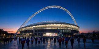 England vs Spain: Nations League Kickoff Time, TV and Tuchel’s Absences Ahead of Wembley Clash Floodlit football stadium with a large white arch at dusk as fans walk toward it ahead of England vs Spain