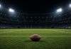 Cowboys Agree to Trade for Steelers Cornerback Joey Porter Jr. A football resting on the grass of an empty floodlit stadium at night, with white yard lines and empty stands