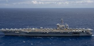 US Sends Third Aircraft Carrier Toward Iran as Another Tanker Is Hit in Hormuz Aircraft carrier USS Theodore Roosevelt under way at sea in a side view, with fighter jets parked on its flight deck, on open blue water