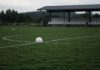 Cristiano Ronaldo Leaves Portugal Camp, Then Portugal Beat Denmark 4-2 Without Him A white football resting on the center circle of an empty training pitch, with orange cones and a covered team bench in the background on an overcast day