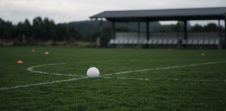 Cristiano Ronaldo Leaves Portugal Camp, Then Portugal Beat Denmark 4-2 Without Him A white football resting on the center circle of an empty training pitch, with orange cones and a covered team bench in the background on an overcast day