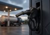 G7 Agrees 100 Million Barrel Oil and Diesel Release After Trump Export Ban Threat A black diesel fuel nozzle in its holder on a pump at a filling station at dusk, with a tanker truck blurred in the background